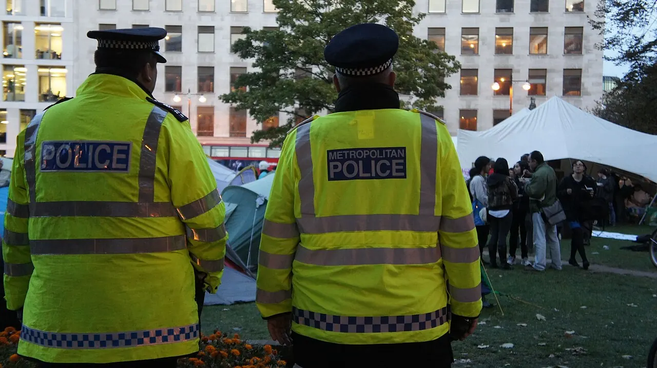 Two London Metropolitan Police officers watch a protest camp